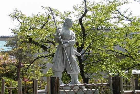 A stone statue on Mount Iimori, facing toward distant Tsurugajo Castle