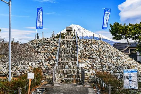 A Fujizuka mound with stone steps, with the real Mt. Fuji visible behind it