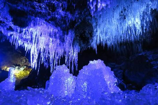 Lit-up icicles lining the interior of an ice cave