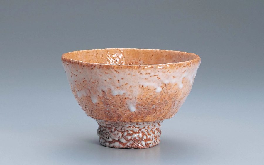 A Hagi-yaki tea bowl with a pale loquat-colored glaze and white mottled patterning