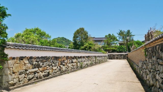 A street lined with earthen walls in the Horiuchi district, with mountains visible in the distance