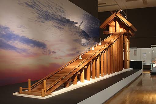 A reconstructed model of the ancient great hall's stepped approach, displayed against an evening sky