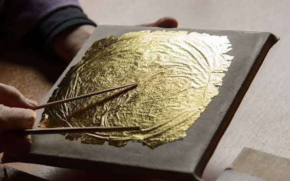 A craftsman handling gold leaf
