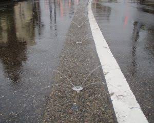 Snow-melting sprinklers spraying water on a winter road