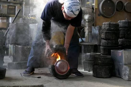 An artisan pouring molten iron into a mold at a workshop