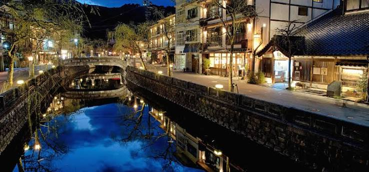 Willow trees lit at night along the Otani River in Kinosaki Onsen